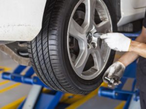 Je Reviens Tout De Suite. Mécanicien Tenant Un Pneu Au Garage De  Réparation. Remplacement Des Pneus Hiver Et été.