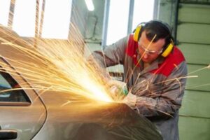 collision repairs service. auto repair mechanic grinding car body by grinder